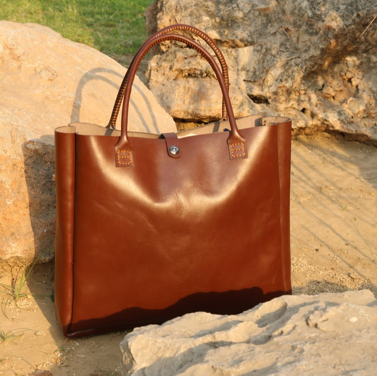 Brown leather tote bag on a stone surface with a natural background