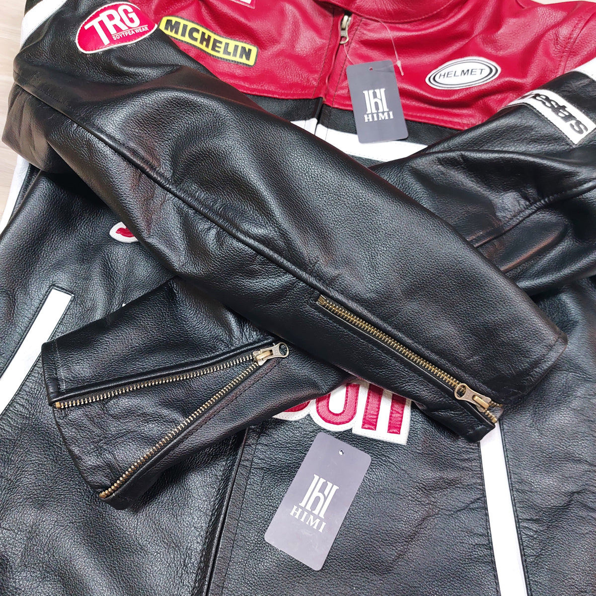 Black leather jacket with gold zipper and visible branding on a white background