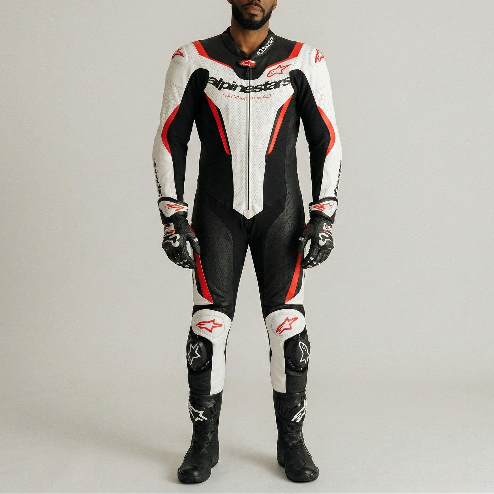 Person wearing a black, white, and red Alpinestars racing suit on a gray background