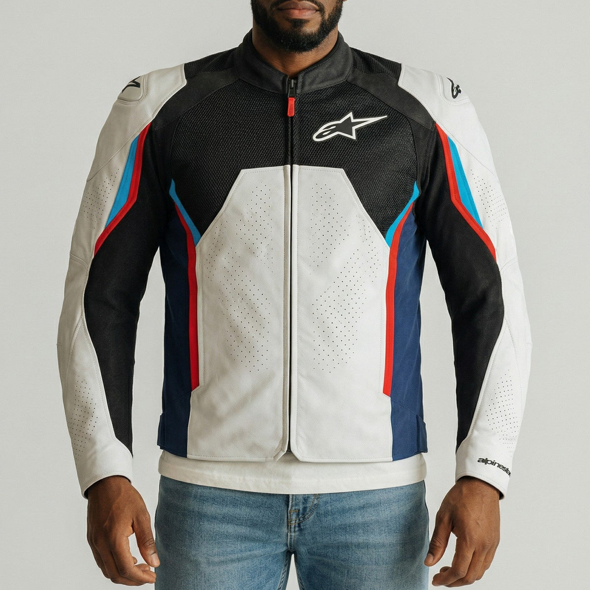 Man wearing a black, white, and blue alpinestars ast v3 air motorcycle jacket with a brand logo on a gray background