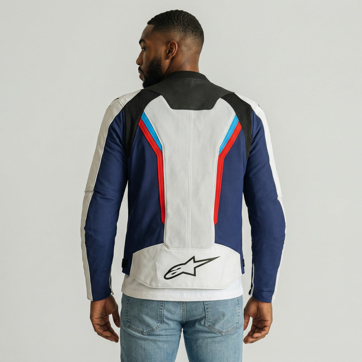 Person wearing a colorful alpinestars ast v3 air jacket with a brand logo on a plain background