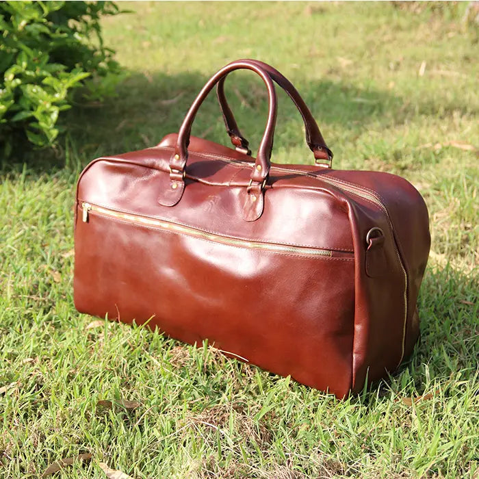 Brown leather duffel bag on grass