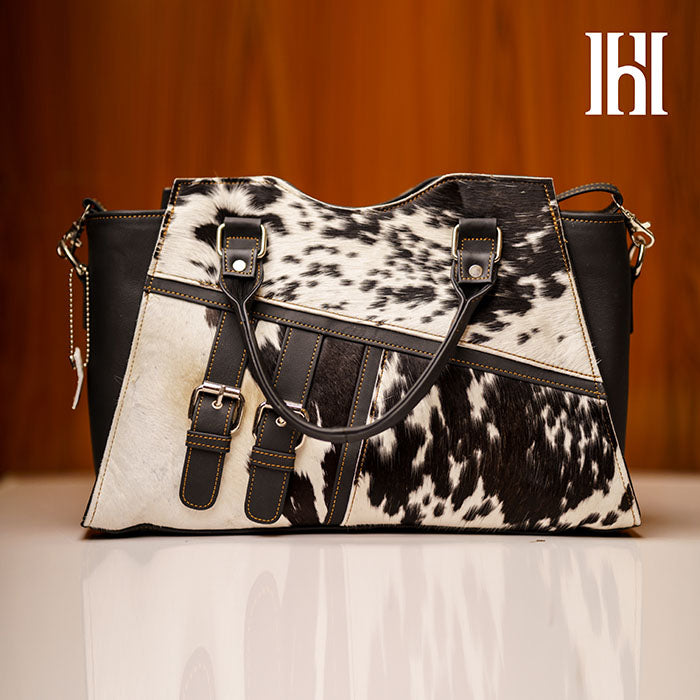 A black and white leather handbag with a fur-like pattern, featuring a zipper closer and two compartments.