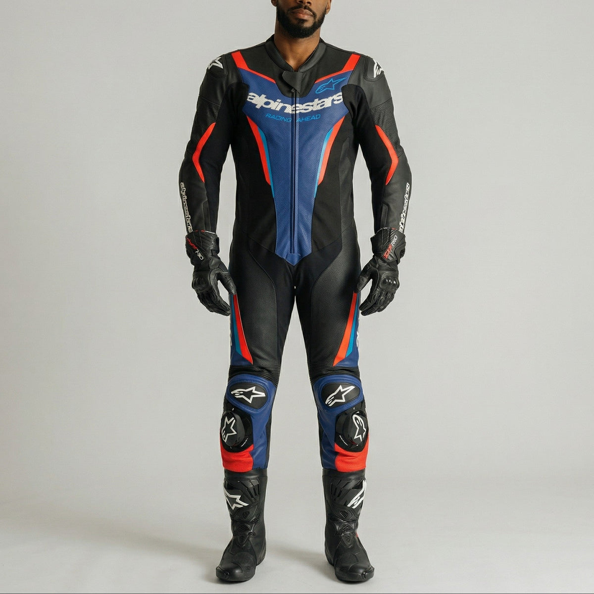 Person wearing a black, blue, and red motorcycle suit with visible branding on a gray background