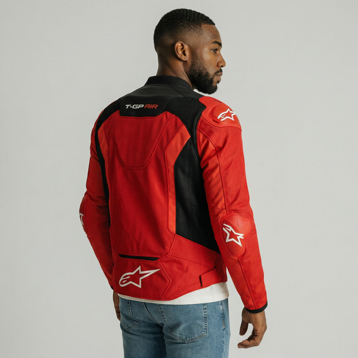Man wearing a red and black t-gp plus r air jacket with a logo on a gray background