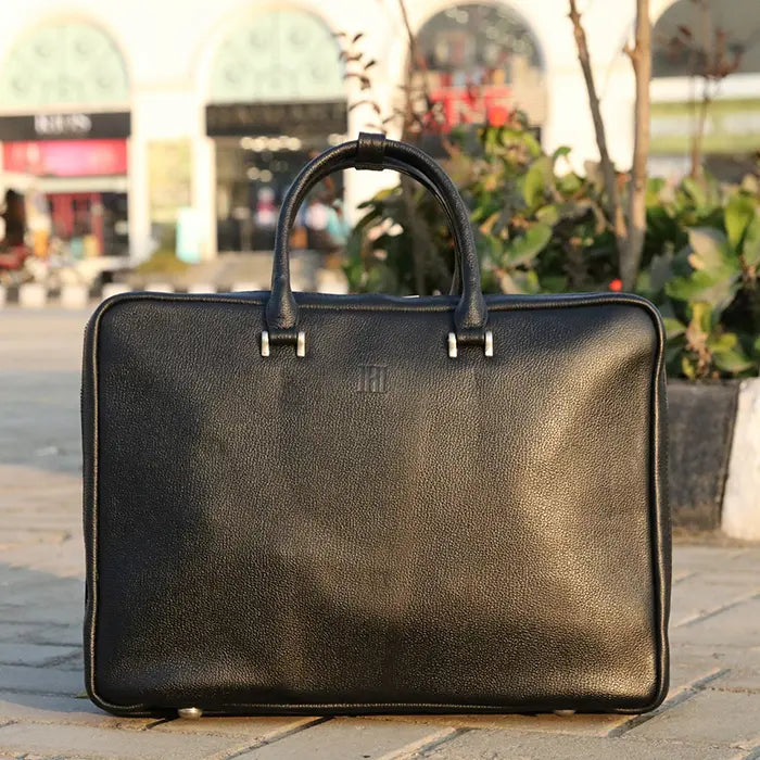 Black leather briefcase on a stone pavement with blurred background