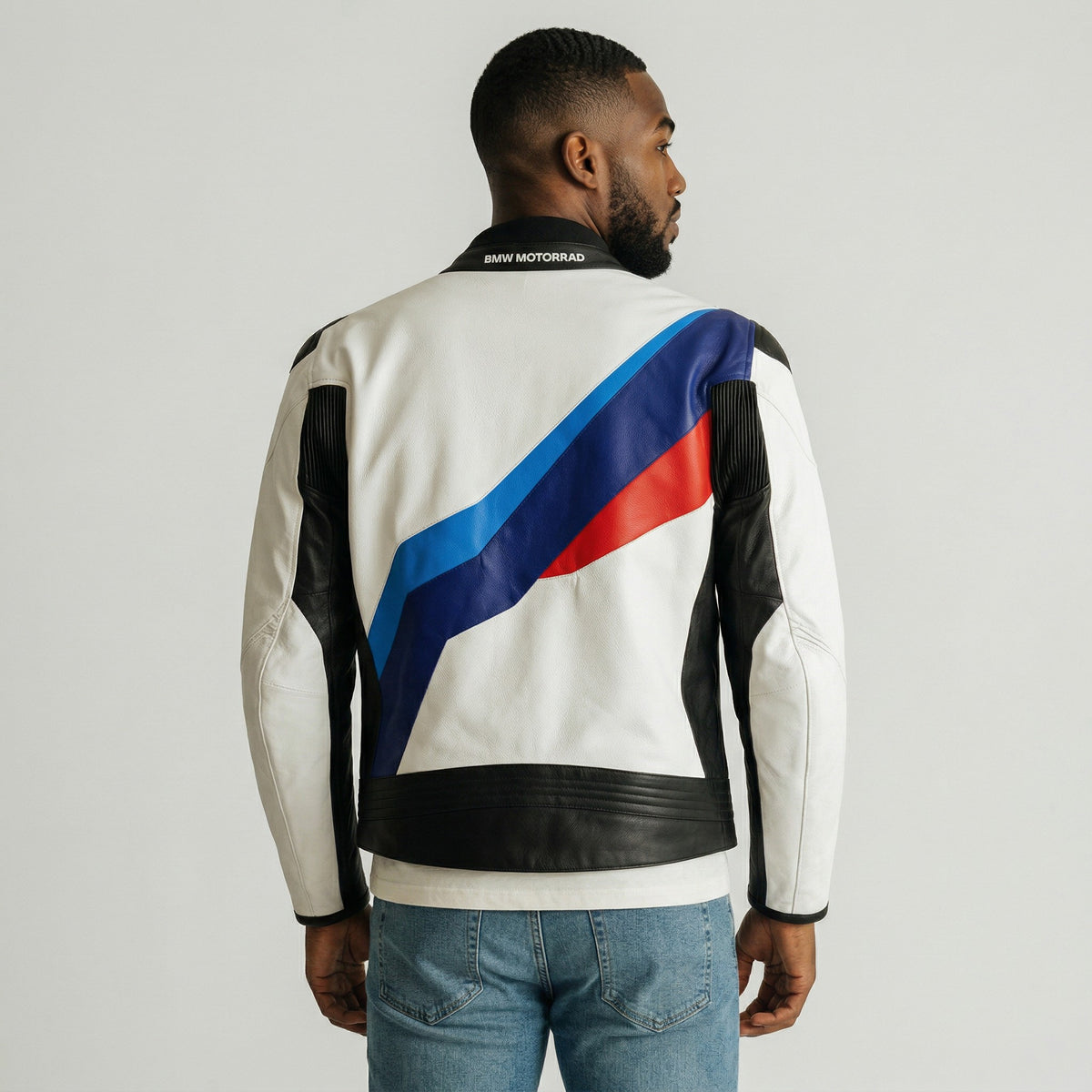 Man wearing a white BMW Downforce leather jacket with blue and red stripes on a gray background