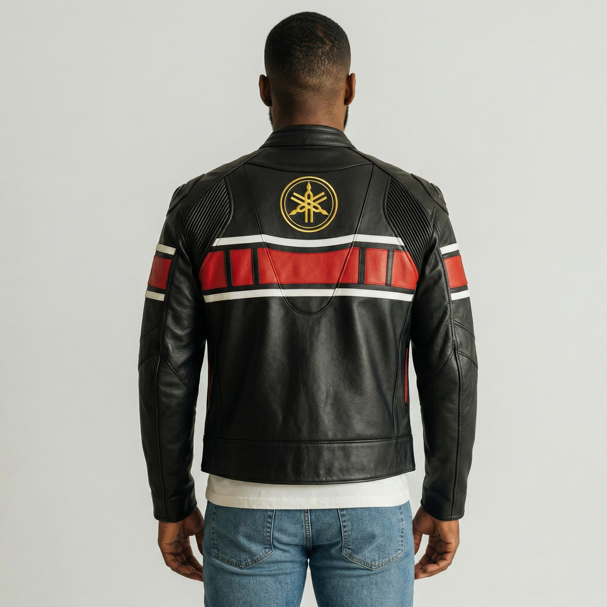 Person wearing a black leather jacket with red and white stripes on the back, featuring a logo, against a gray background.