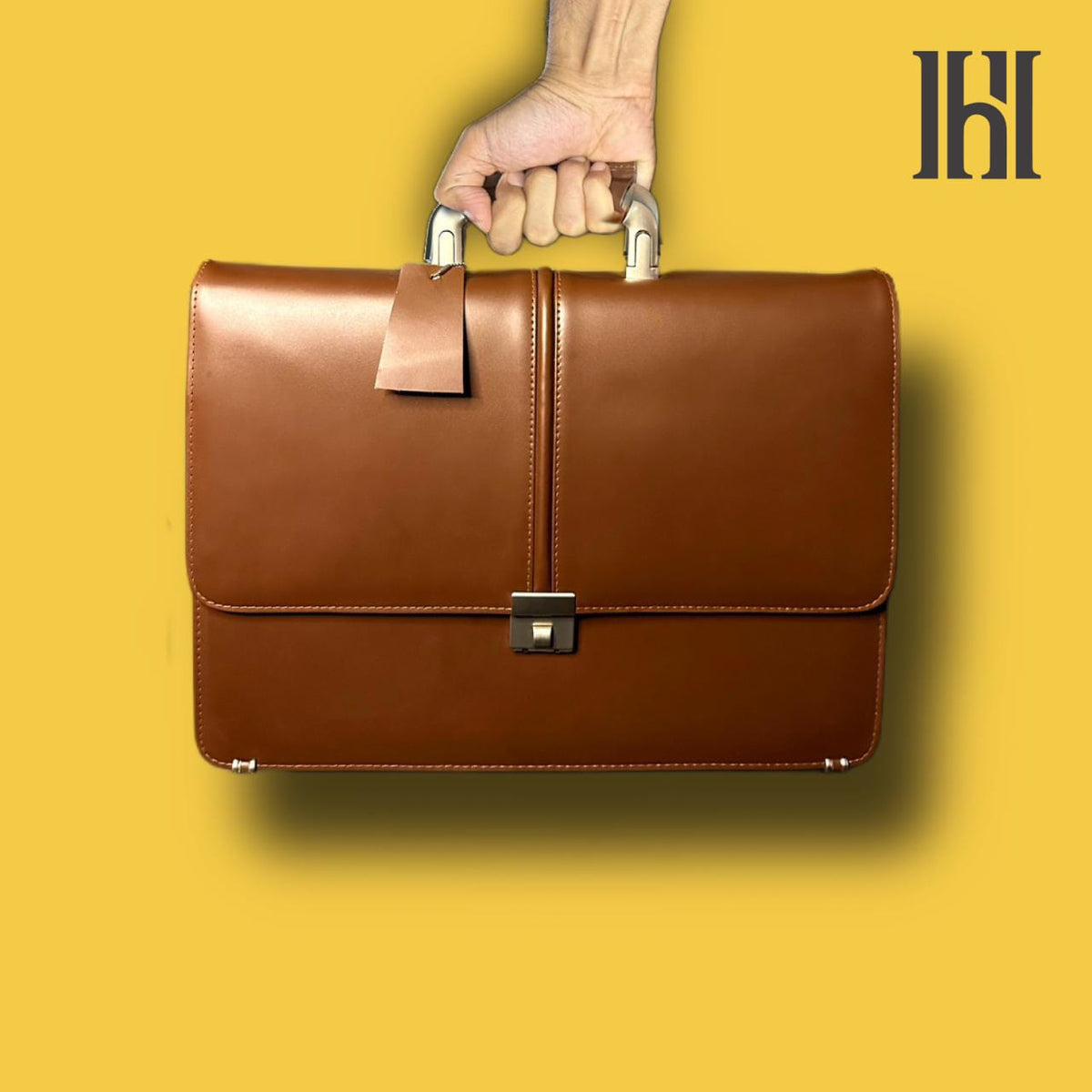 A person is holding a brown premium leather laptop bag with a sleek design and a shoulder strap.