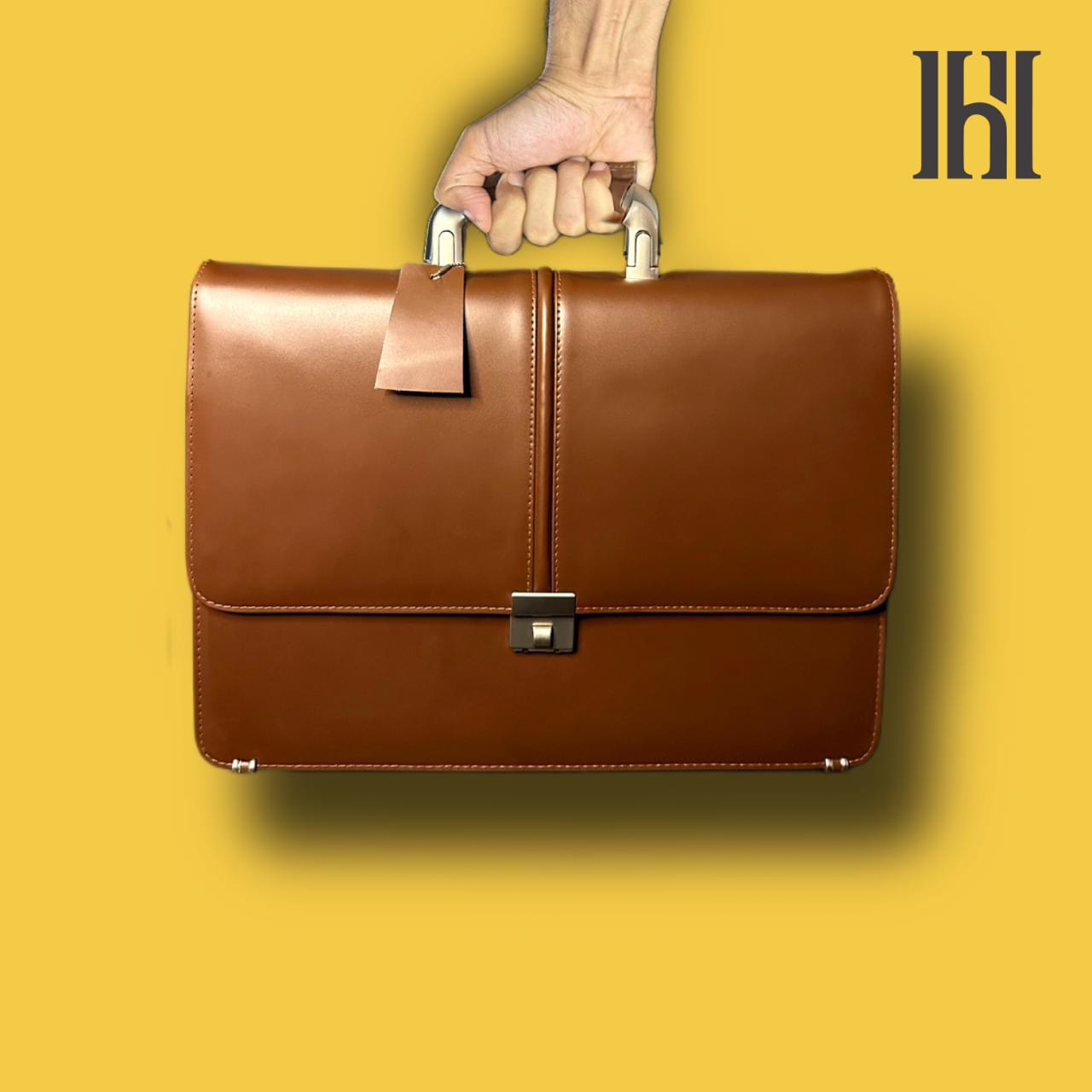A person is holding a brown premium leather laptop bag with a sleek design and a shoulder strap.