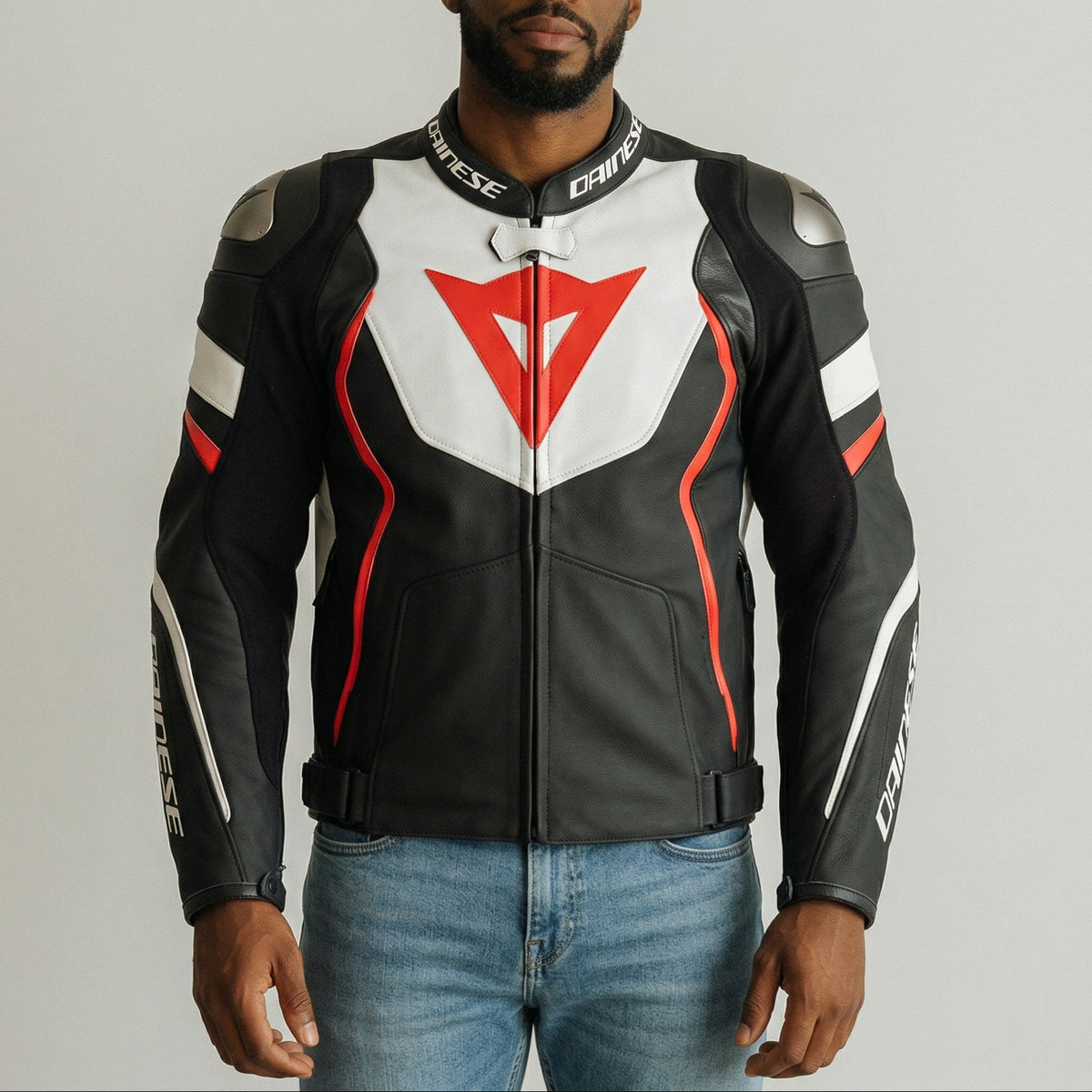 Man wearing a black, white, and red dainese motorcycle jacket with a visible brand logo on a gray background